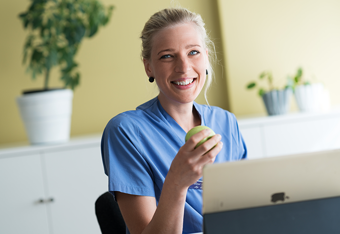 Dietist med ett äpple som sitter och jobbar med ND Kost